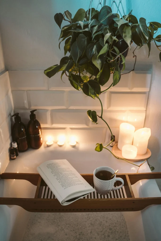 A bubble bath with lit candles. A board across the bath with an open book and a cup of tea.