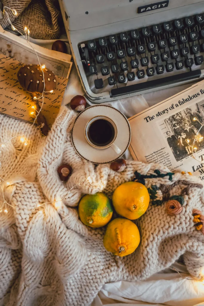 Flat lay with lemons, a coffee cup, books, and scrap papers and a typewriter